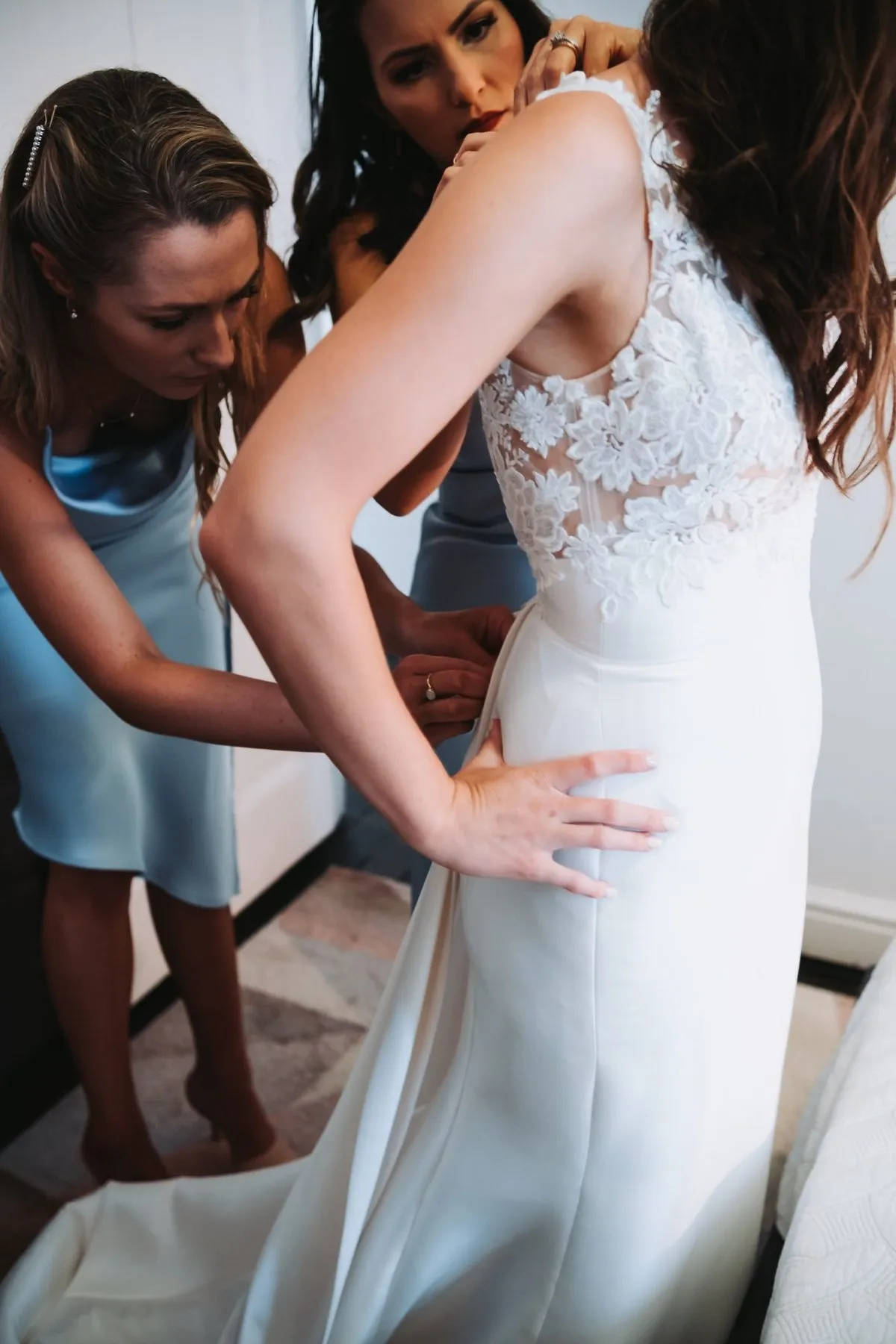 Bridesmaids helping bride into wedding dress